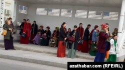 Jemgyýetçilik transport duralgasyndaky aýallar. Aşgabat, 2024-nji ýylyň marty.