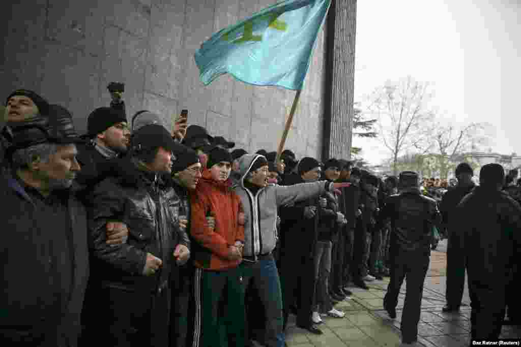 Крымские татары держат флаг своего народа во время митинга у парламента Крыма в Симферополе, 26 февраля 2014 года. Неделей ранее крымский политик поднял вопрос о возможности «отсоединения» полуострова от Украины. Протестующие на Майдане в Киеве в то время находились в процессе отстранения от власти пророссийского президента Виктора Януковича, позже эти протесты стали называть «революцией достоинства». 