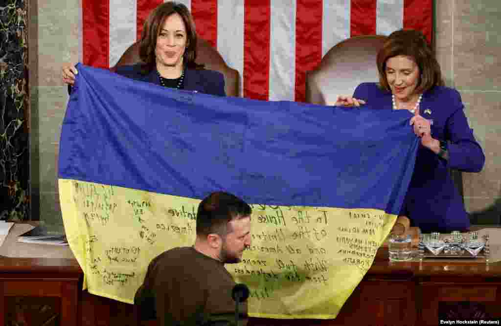 Харрис (слева) и спикер Палаты представителей США Нэнси Пелоси держат украинский флаг, привезенный президентом Украины Владимиром Зеленским из Бахмута во время его выступления на совместном заседании Конгресса США (21 декабря 2022 года). «Бахмут стоит, – сказал Зеленский под аплодисменты. – Украина держит свои позиции и никогда не сдастся».