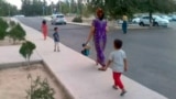 Turkmenistan. Mother with her children walking on the sidewalk. 2021.