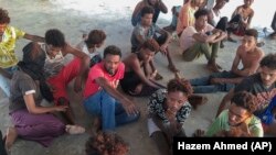 Spašeni migranti sjede na obali koja se nalazi 100 kilometara istočno od Tripolija u Libiji, juli, 2019.