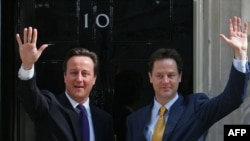 David Cameron (L) i Nick Clegg mašu novinarima nakon što su 12. maja 2010. predstavili plan njihove vlade
