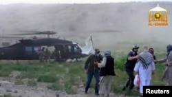 FILE: A Blackhawk helicopter waits as US Army Sergeant Bowe Bergdahl (2nd R, back facing) is being led to the American military during his release at the Afghan border, in this still image from video released on June 4.