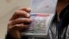 A member of the Al-Murisi family, Yemeni nationals who were denied entry into the United States because of a recent travel ban, shows the cancelled visa in their passport from their failed attempt to enter the country. (file photo)