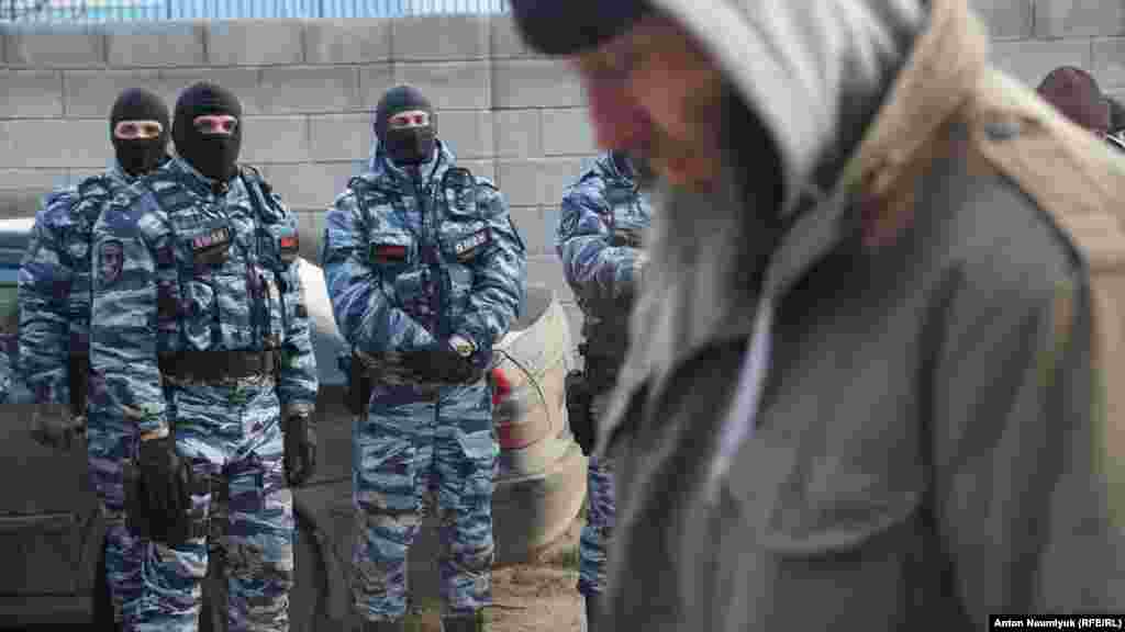 Пожилой мусульманин проходит мимо российских силовиков, заблокировавших собрание крымскотатарской правозащитной организации «Крымская солидарность», отстаивающей права почти двух сотен крымчан, преимущественно крымских татар и мусульман, которых правозащитники считают политзаключенными, Судак, 28 января 2018 года, фото - Антон Наумлюк.