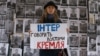 Громадська активістка під час акції протесту біля офісу телеканалу «Інтер» на тлі фотографій українських воїнів, які загинули на Донбасі у війні України проти Росії. Київ, 11 грудня 2014 року