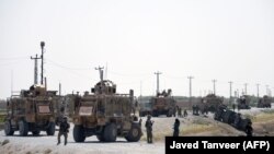 FILE: NATO soldiers keep watch near the wreckage of their vehicle at the site of a Taliban suicide attack in Kandahar on September 15.