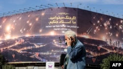 مردی در میدان ولی‌عصر تهران در حال عبور از کنار یک تابلوی تبلیغاتی جمهوری اسلامی علیه اسرائیل