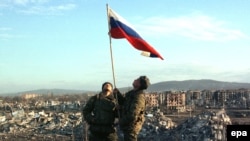 Російські солдати встановлюють прапор Росії в центрі Грозного. Чечня, лютий 2000 року. Грозний російська армія захопила тільки після того, як практично знищила його бомбардуваннями, зокрема і касетними боєприпасами