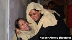 A police officer comforts a relative after a police officer and three of his family members were shot dead in Quetta on November 15.