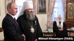 Президент Росії Володимир Путін (ліворуч) під час вручення державної нагороди Росії наміснику Києво-Печерської лаври митрополиту УПЦ (Московського патріархату) Павлу (Петру Лебідю) (другий зліва). Праворуч – патріарх Московський Кирило. Київ, 27 липня 2013 року