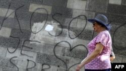 Belgradda bir zenan “Kosowa Serbiýanyň kalbydyr” diýlip ýazylan diwaryň deňinden geçip barýar, 23-nji iýul, 2010-njy ýyl.