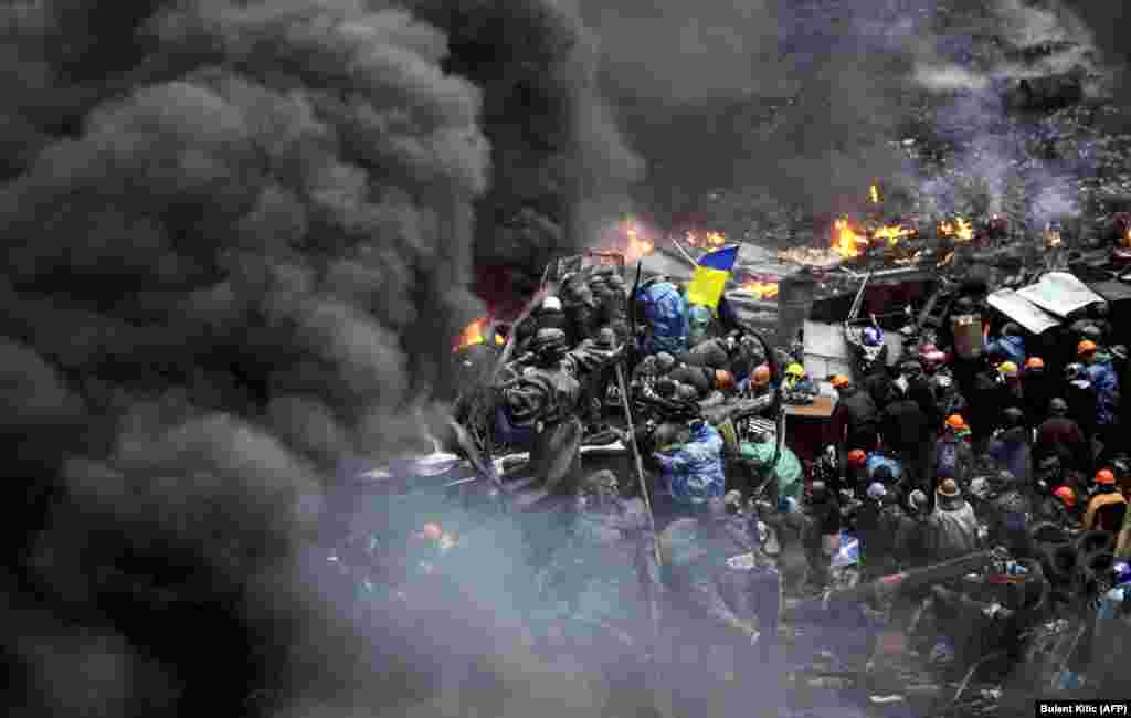 Demonstranti stoje iza zapaljenih barikada tokom sukoba sa policijom, 20. februar 2014.