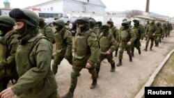 Rus harbylarydygy çaklanýan adamlar Krymyň Simferopol şäherinden ýöräp barýarlar.