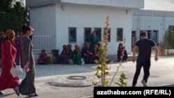 Adamlar boş bankomatlaryň öňünde oturyp, pula garaşýarlar. Bäherden, Türkmenistanyň Ahal welaýaty, awgust, 2020. 