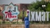 Женщина моет надпись из объемных букв "70 лет Ахмат-Хаджи Кадыров" на одной из улиц города Грозный в Чечне. Россия, 2021 год 