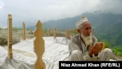 Eighty-year-old Gul Shirin prays next to the fresh graves of 13 family members who died in flooding in Swat Valley in August.