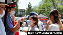 Bişkekde bir polisiýa işgäri adamlaryň beden gyzgynlygyny ölçeýär. Bişkek, Gyrgyzystan. 26-njy maý, 2020-nji ýyl.