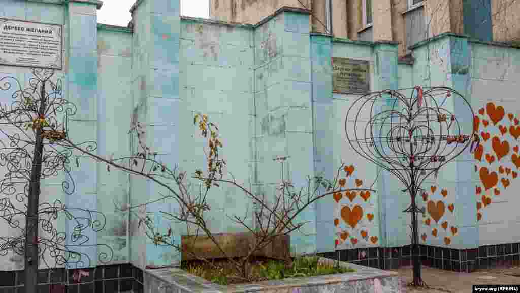 «В гнездо монетку брось – семья не будет врозь» написано на табличці над кованим «деревом бажань». Праворуч від нього – «дерево кохання та щастя»