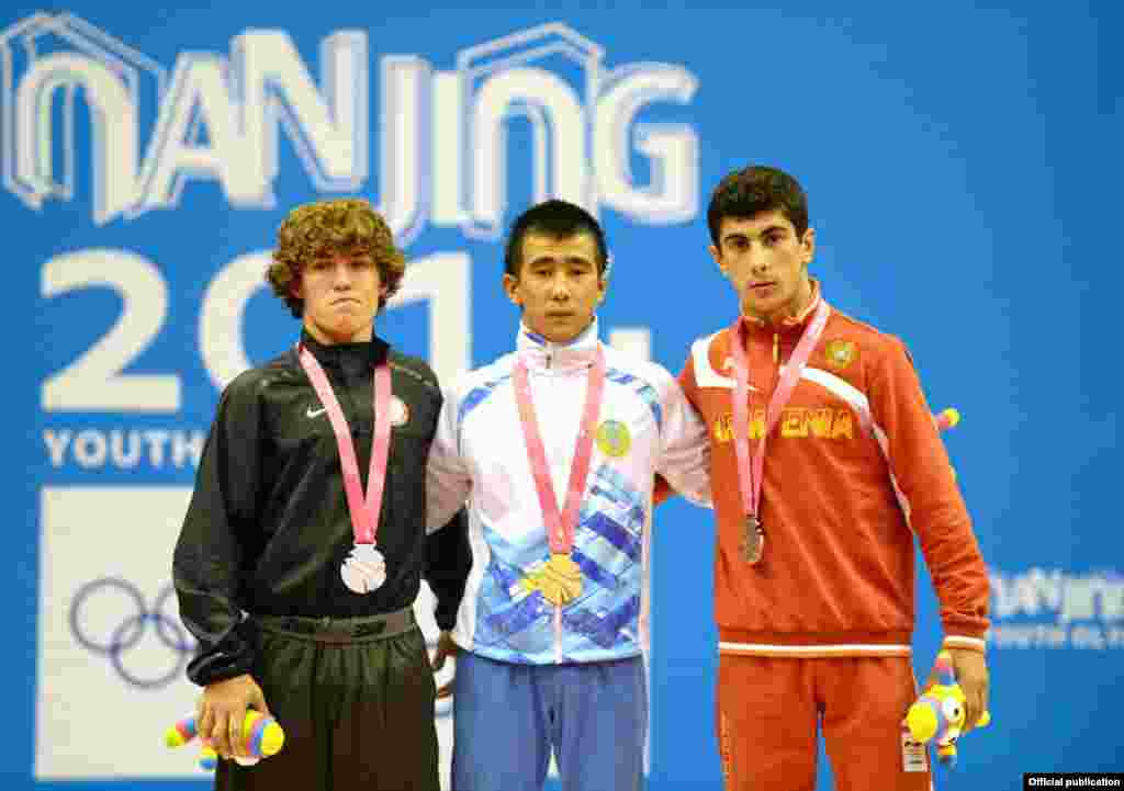 Казахстанский спортсмен Мухамбет Куатбек (в центре) стал чемпионом юношеской Олимпиады среди борцов-вольников в весе до 54 килограммов.
