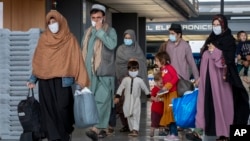 Kabuldan ewakuasiýa edilen owganystanly maşgalalar Waşingtonyň Dulles aeroportyndan ýöräp barýarlar. Sentýabr, 2021 ý.
