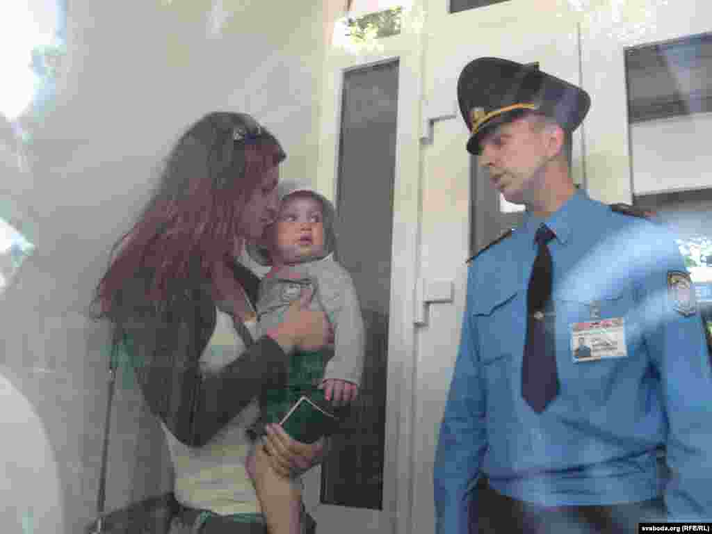 Жонку журналіста Аксану Пачобут з дзіцём на руках ў тамбуре суду не пускае ўнутр міліцыянт