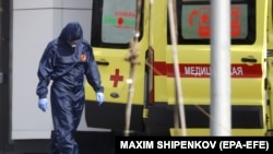 COVID-19 билан хасталанган беморни олиб кетишга ҳозирлик кўраётган тиббиёт ходими, 1 май, 2020